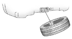 5. Tilt the retainer and slip it through the wheel opening to remove the spare tire from the cable.